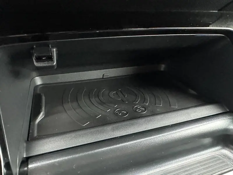 Gros plan sur le chargeur sans fil noir intégré dans la console centrale du Peugeot 208 1.2 Hybrid 110ch GT 2025.