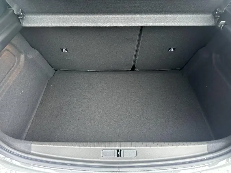 Coffre ouvert vu de dessus d'une Peugeot 208 1.2 Hybrid 110ch GT 2025, intérieur noir et tapis plat.