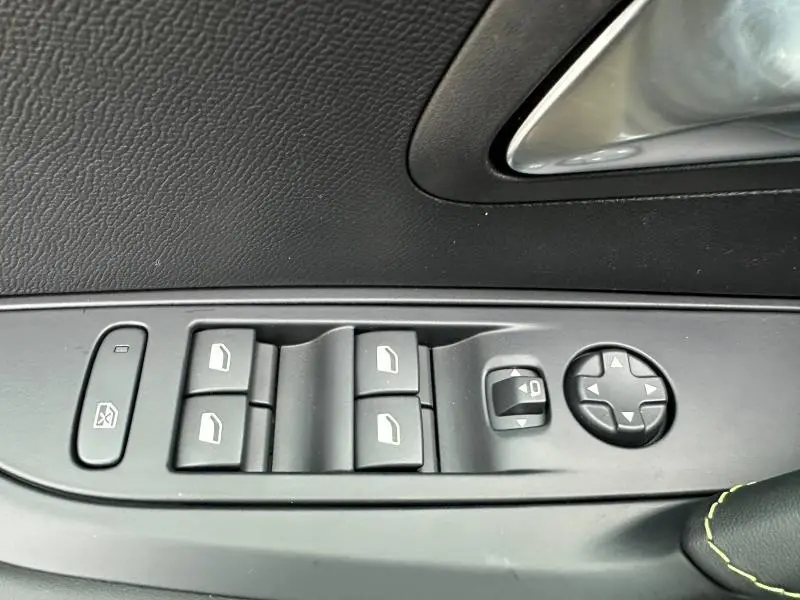 Panneau de commandes des vitres et rétroviseurs côté gauche intérieur d'une Peugeot 208 1.2 Hybrid 110ch GT 2025 noire.