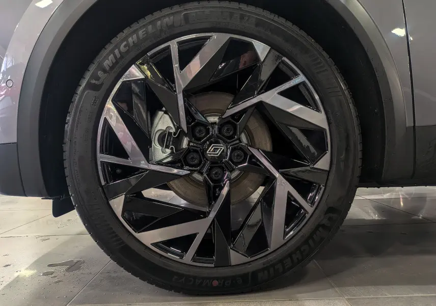 Gros plan sur la roue avant gauche du Renault SYMBIOZ gris Cassiopé avec jante noire et argentée au design anguleux.