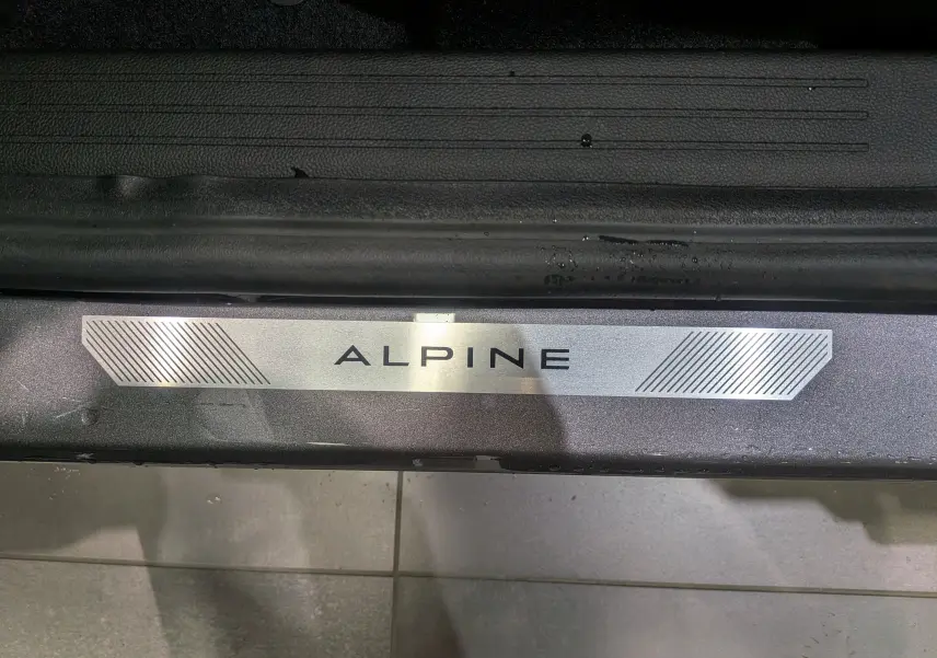 Gros plan sur la plaque de seuil de porte Alpine du Renault Symbioz gris Cassiopé, soulignant la finition Esprit Alpine.