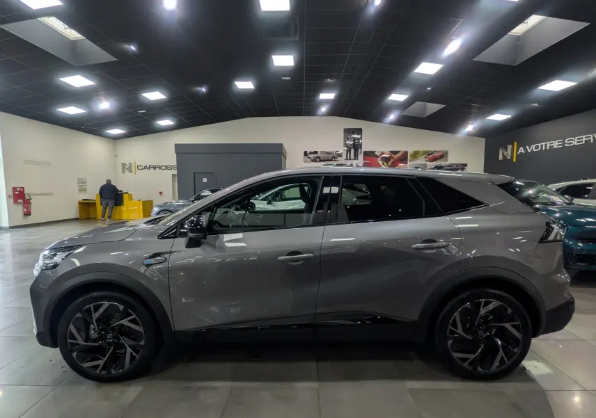 Profil côté gauche du Renault SYMBIOZ gris Cassiopé, version E-Tech full hybrid 160 ch Esprit Alpine, en showroom lumineux.