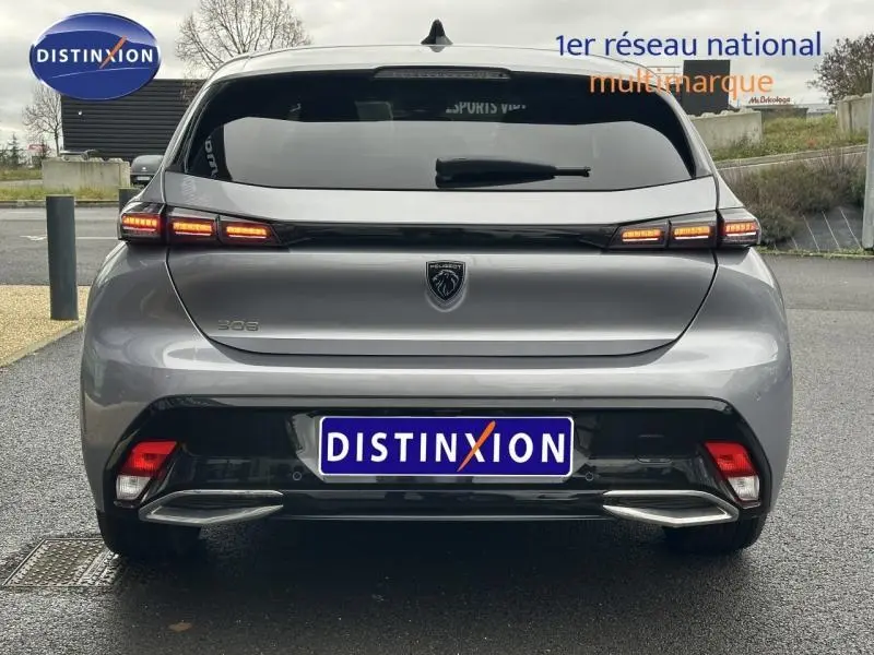 Vue arrière d'une Peugeot 308 2024 gris Artense avec feux LED allumés et lunette arrière surteintée.