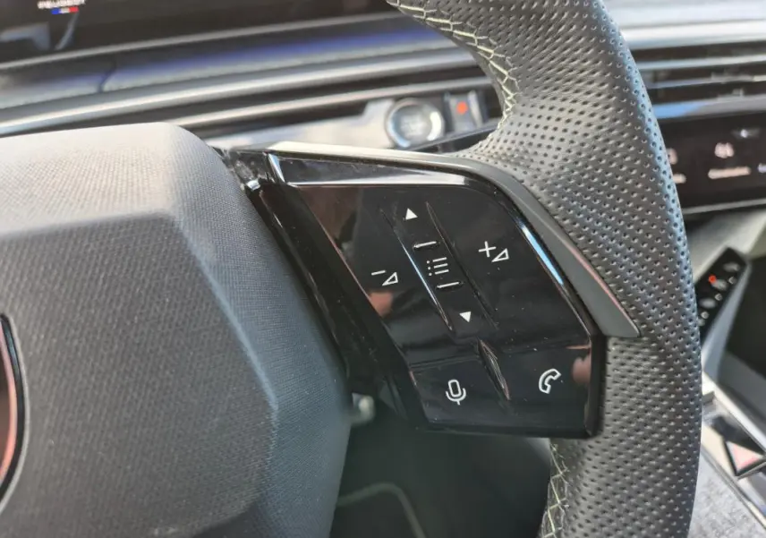 Gros plan sur le côté droit du volant perforé du Peugeot 3008 Hybrid 136 e-DCS6 GT gris clair, avec commandes vocales et appels.