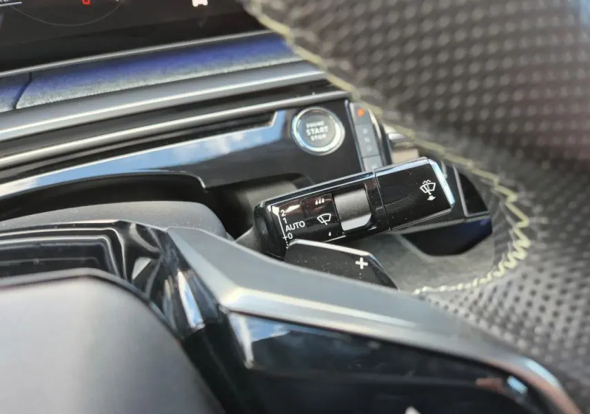 Gros plan sur la commande d’essuie-glace et le bouton start/stop du Peugeot 3008 Hybrid gris clair, intérieur moderne.