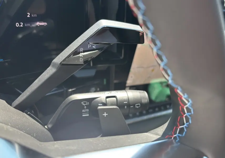 Gros plan sur la commande de boîte automatique et palettes au volant avec surpiqûres tricolores du Renault Austral E-Tech 200 Esprit Alpine.