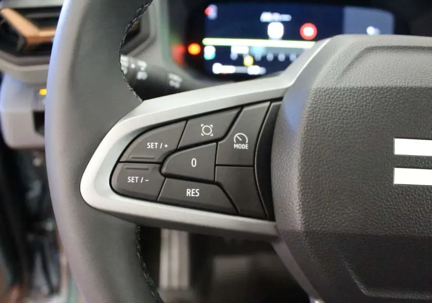 Gros plan sur le volant cuir du Dacia Bigster gris schiste, avec commandes de régulateur de vitesse visibles.