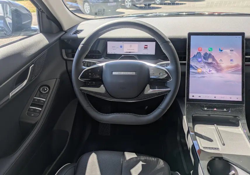 Vue intérieure centrée sur le volant noir carbone et le grand écran tactile vertical du tableau de bord du JAECOO J5.