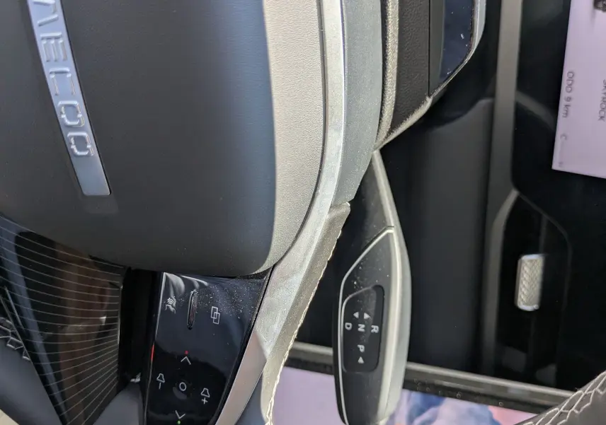 Gros plan sur le volant noir cuir du JAECOO J5 avec commandes intégrées et levier de vitesses automatique visible.