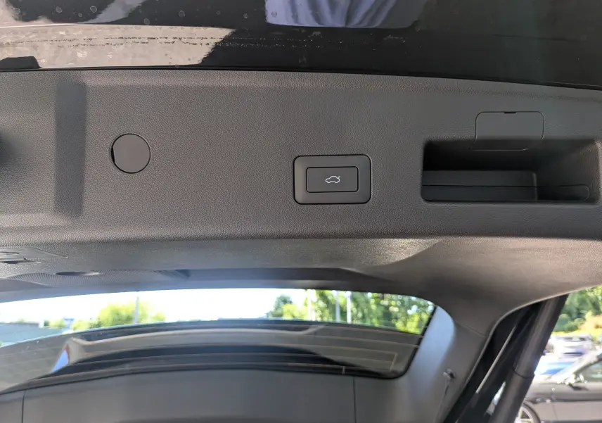 Gros plan sur le bouton d'ouverture électrique du coffre, à l'intérieur du hayon du JAECOO J5 noir carbone 2026.