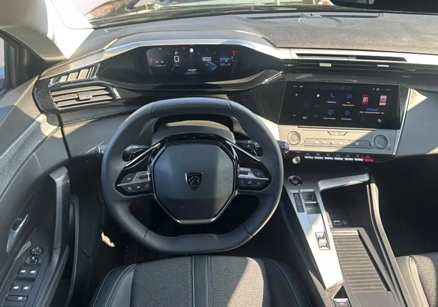 Vue intérieure frontale du poste de conduite de la Peugeot 308 gris artense, avec volant multifonction et écran tactile.