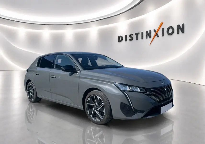 Peugeot 308 gris artense vue 3/4 avant droit en showroom avec jantes alliage et calandre noire distinctive.