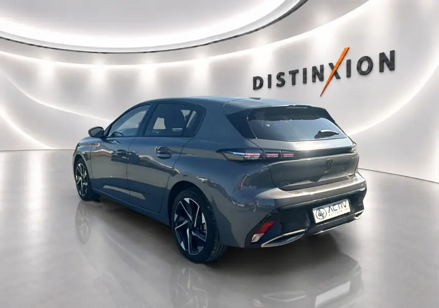 Peugeot 308 gris Artense vue 3/4 arrière droit dans un showroom lumineux avec jantes alliage noires.