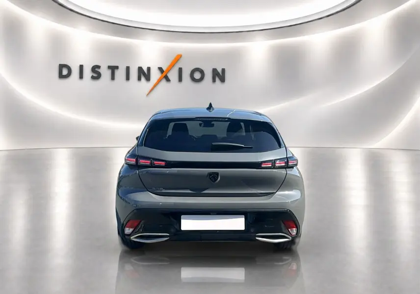 Vue arrière d'une Peugeot 308 1.5 BlueHDi 130 Allure gris Artense dans un showroom lumineux avec logo Distinxion en arrière-plan.