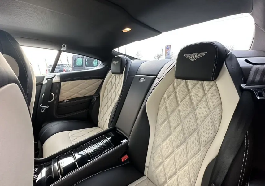 Vue intérieure arrière droite de la Bentley Continental GT 2013 noire, sièges cuir beige matelassé avec logo Mulliner brodé.