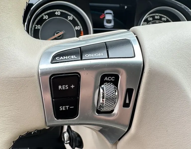 Gros plan sur les commandes de régulateur de vitesse sur le volant cuir beige de la Bentley Continental GT noire 2013.