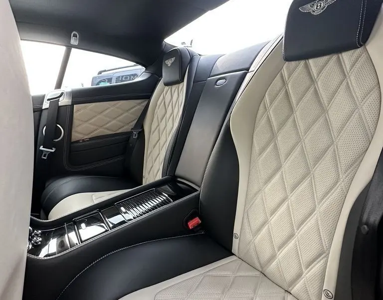 Vue intérieure arrière de la Bentley Continental GT 4.0 V8 Mulliner 2013, sièges cuir noir et beige avec surpiqûres diamantées.