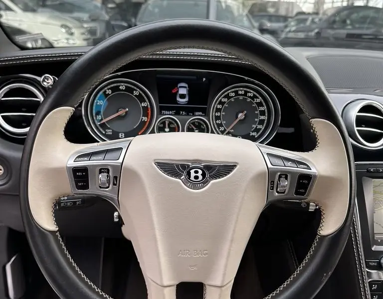 Vue intérieure centrée sur le volant bicolore noir et beige de la Bentley Continental GT Mulliner 2013 avec tableau de bord visible.