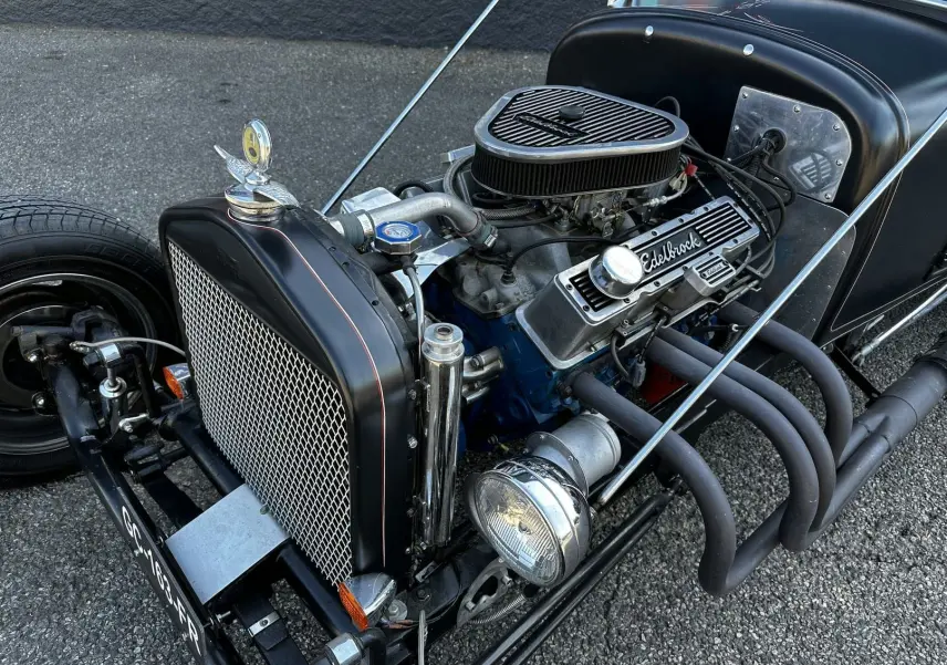 Vue avant droite du Ford T Hot Rod noir avec moteur V8 apparent et échappements latéraux mat.