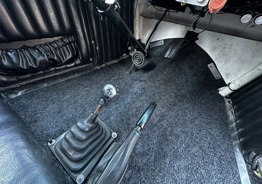 Vue rapprochée du levier de vitesse chromé tête de mort et frein à main cuir dans l'habitacle noir du Ford T Hot Rod 1923.