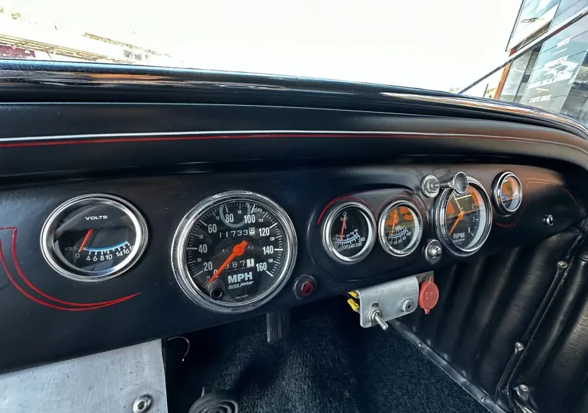 Tableau de bord noir du Ford T Hot Rod 1923 avec compte-tours, voltmètre et compteur de vitesse en vue rapprochée.