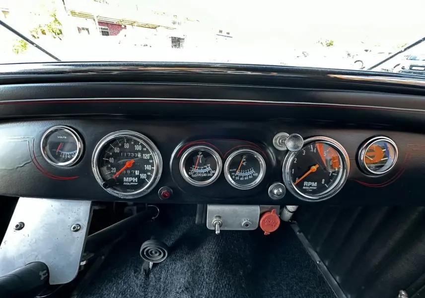 Tableau de bord noir du Ford T Hot Rod V8 1923 avec compte-tours, compteur de vitesse et indicateurs ronds chromés.