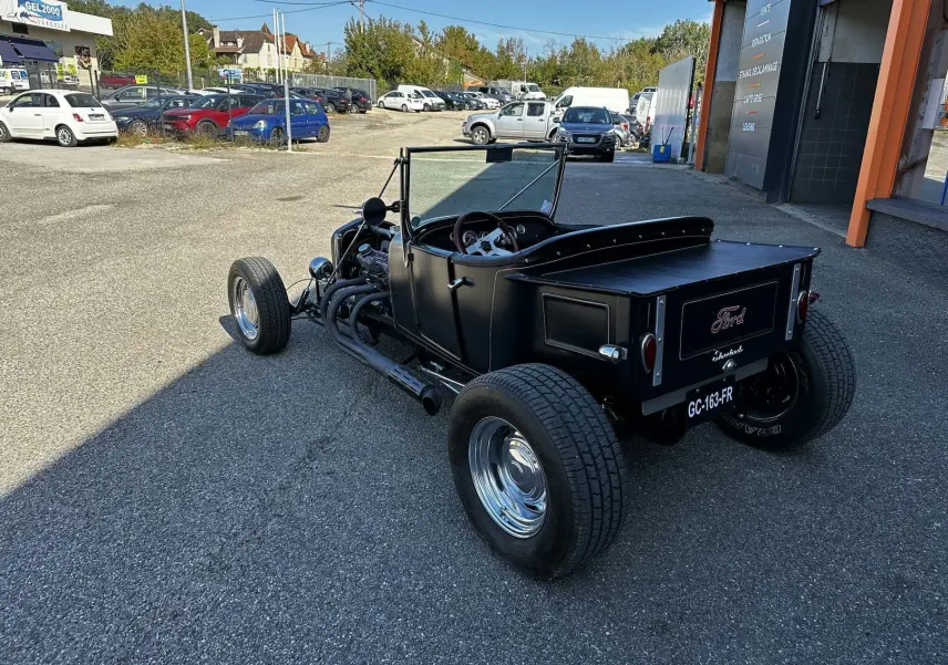 Vue 3/4 arrière droite d'une Ford T Hot Rod V8 noire décapotable avec jantes chromées et coffre plat.