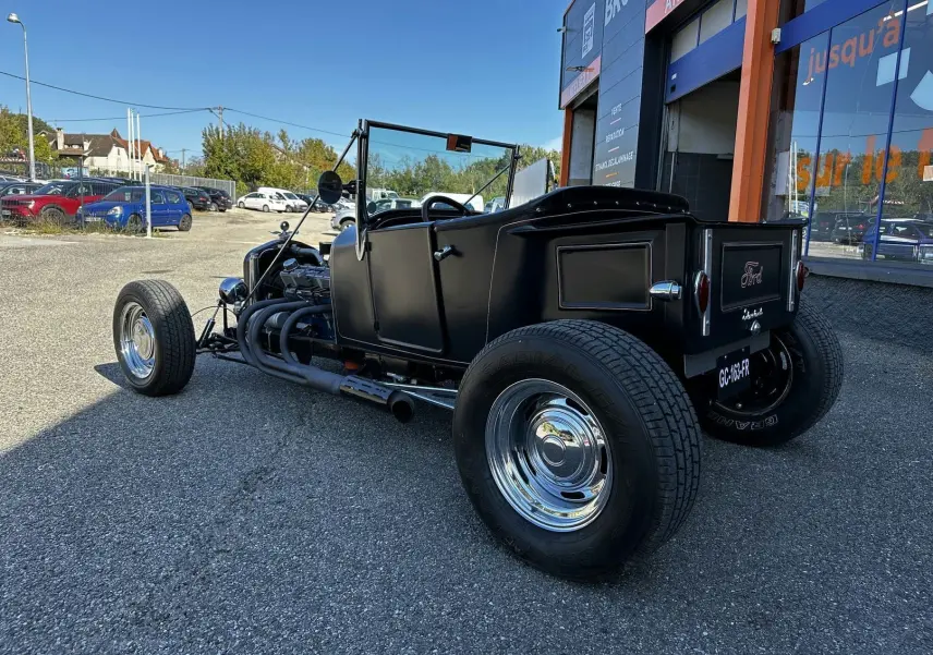 Ford T Hot Rod V8 noir vue 3/4 arrière droit, capote manuelle baissée et échappement latéral chromé visible