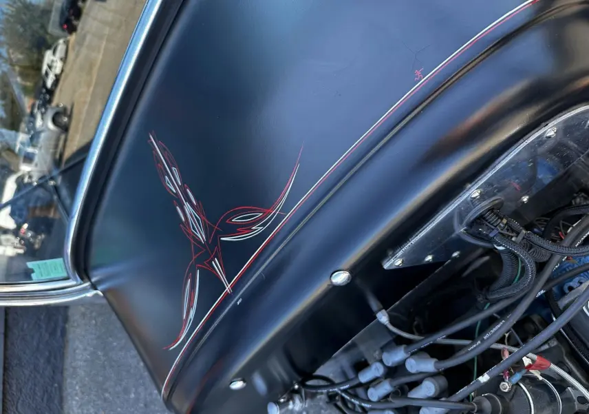 Vue rapprochée du capot noir mat du Ford T Hot Rod 1923 avec motifs rouges et détails du moteur V8 visible.