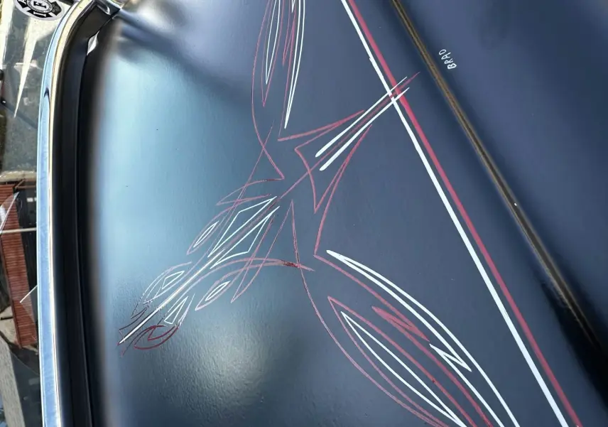Détail de la peinture noire du capot d'un Ford T Hot Rod 1923, avec liserés rouges et blancs signés "Brad".