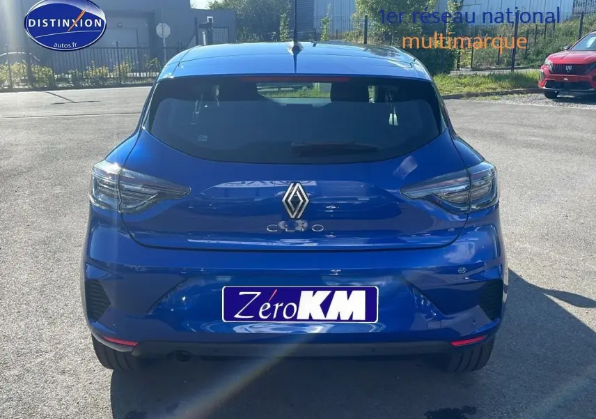 Vue arrière d'une Renault Clio V bleu iron garée en extérieur avec feux arrière LED et becquet distinctif.