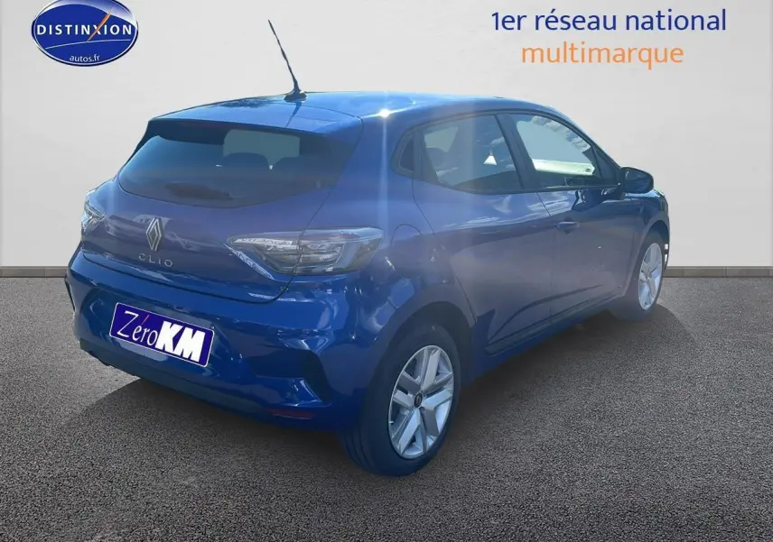 Renault Clio V bleu iron vue 3/4 arrière droit, avec feux arrière LED et becquet sur un sol goudronné.