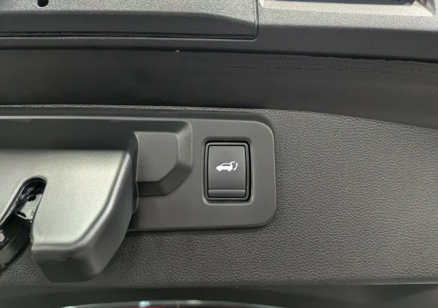 Bouton d'ouverture électrique du coffre sur le panneau intérieur noir d'une Renault SYMBIOZ Gris Cassiopé.