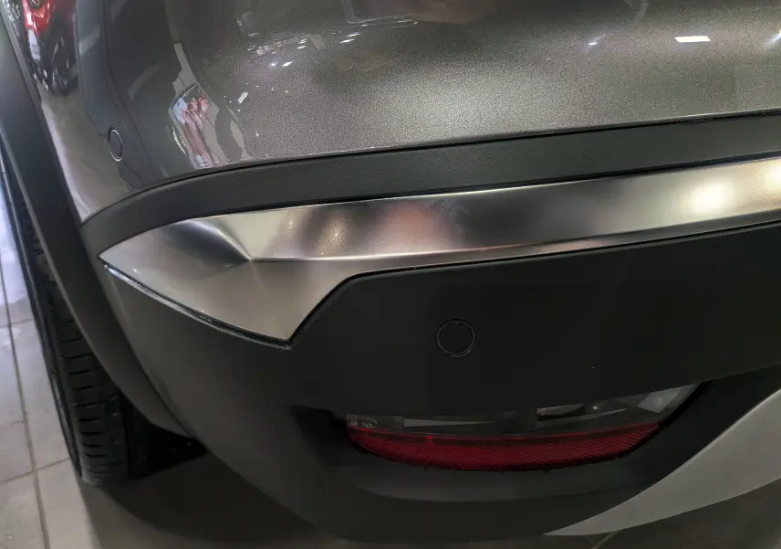 Gros plan sur le pare-chocs arrière gris Cassiopé du Renault Symbioz E-Tech, avec feu antibrouillard et capteur de recul visibles.