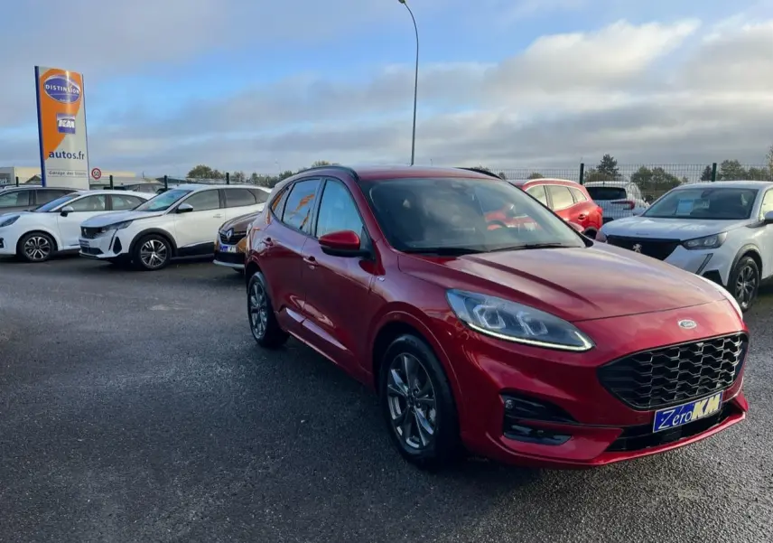 Ford Kuga rouge Lucifer en 3/4 avant droit, avec calandre et jantes alliage ST-Line visibles sur parking.