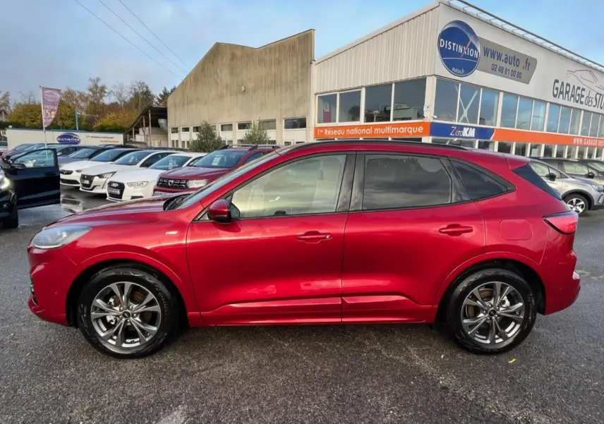 Vue latérale gauche d'un Ford Kuga 1.5 EcoBoost ST-Line rouge Lucifer avec vitres arrière surteintées et jantes alliage 18 pouces.