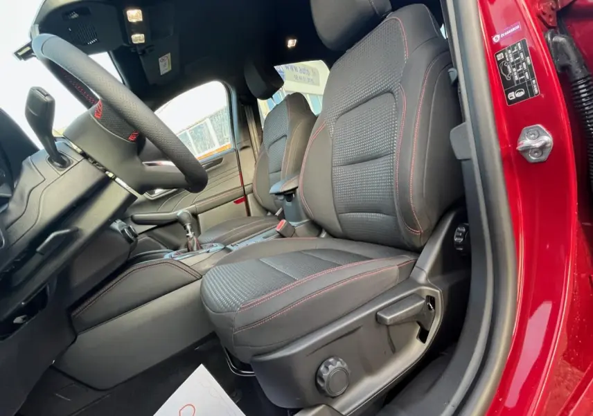 Vue intérieure côté conducteur du Ford Kuga rouge Lucifer 2022, sièges tissu noir avec surpiqûres rouges.