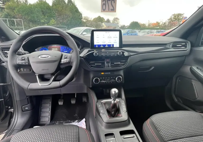 Vue intérieure avant du Ford Kuga 1.5 EcoBoost 2022, tableau de bord noir avec écran tactile et volant multifonctions.