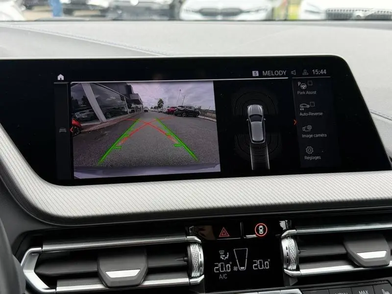 Écran central de la BMW Série 1 118d M Sport montrant la caméra de recul avec vue arrière sur parking et guidage vert et rouge.