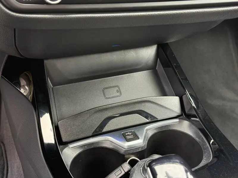 Détail de la console centrale avec porte-gobelets et chargeur sans fil dans une BMW Série 1 118dA M Sport 2022 couleur Saphirschwarz métallisé.