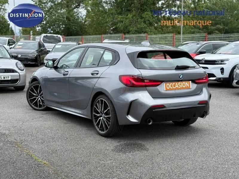 BMW Série 1 118dA M Sport gris saphir, vue 3/4 arrière droit, jantes alliage et double sortie d’échappement.