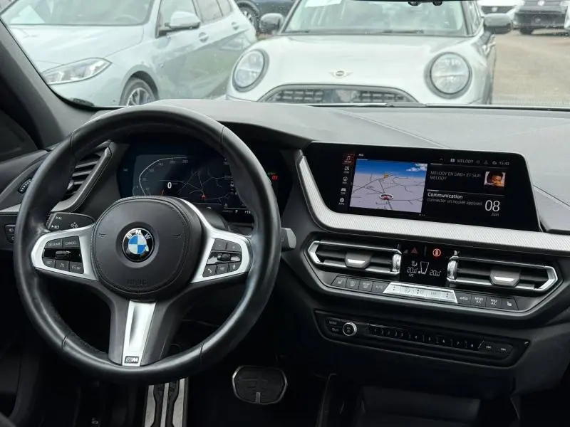 Vue intérieure du tableau de bord et volant cuir multifonction de la BMW Série 1 118dA M Sport 2022, écran tactile et navigation affichés.