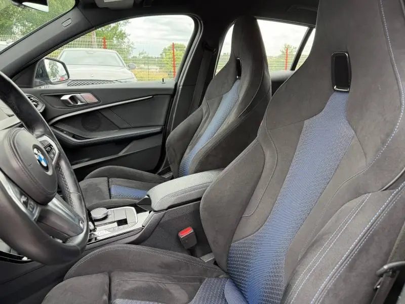 Vue intérieure côté conducteur de la BMW Série 1 118dA M Sport 2022 avec sièges sport en tissu/similicuir noir et bleu.