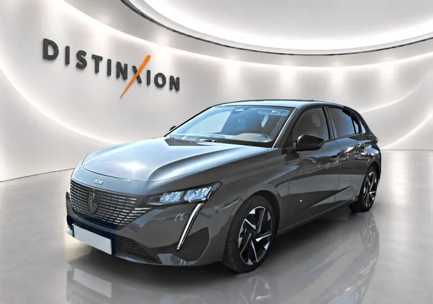 Peugeot 308 gris selenium vue 3/4 avant droit en intérieur avec éclairage moderne et jantes alu distinctives.