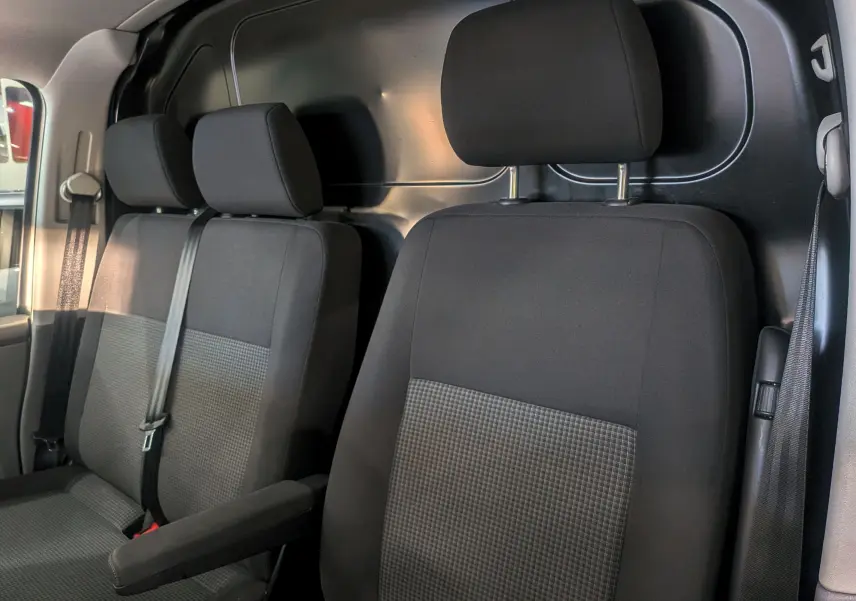 Vue intérieure des sièges avant noirs en tissu du Volkswagen Transporter 6.1 Van, avec cloison métallique arrière visible.