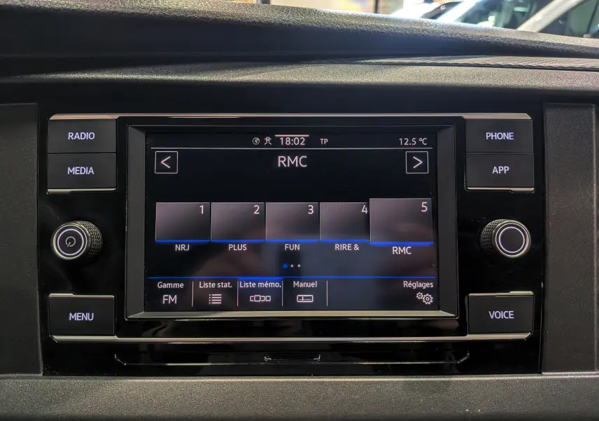 Écran tactile central du Volkswagen Transporter 6.1 blanc, affichant les options radio FM avec boutons autour en vue frontale.