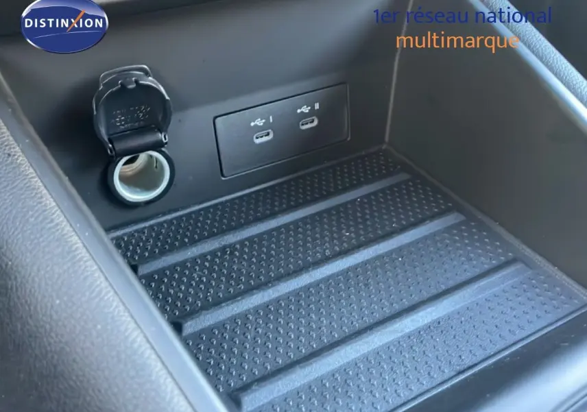 Gros plan sur la console centrale du Renault Symbioz 2025, montrant les ports USB et prise 12V dans un compartiment noir.