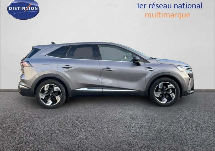 Profil droit du Renault Symbioz E-Tech hybride gris cassiopée métallisé avec jantes noires et argentées, en extérieur sur sol goudronné.