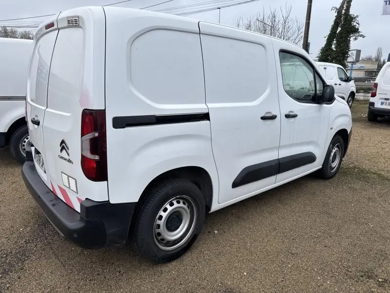 Vue 3/4 arrière droite d'un Citroën Berlingo Fourgon blanc Banquise avec portes battantes arrière et protections noires latérales.