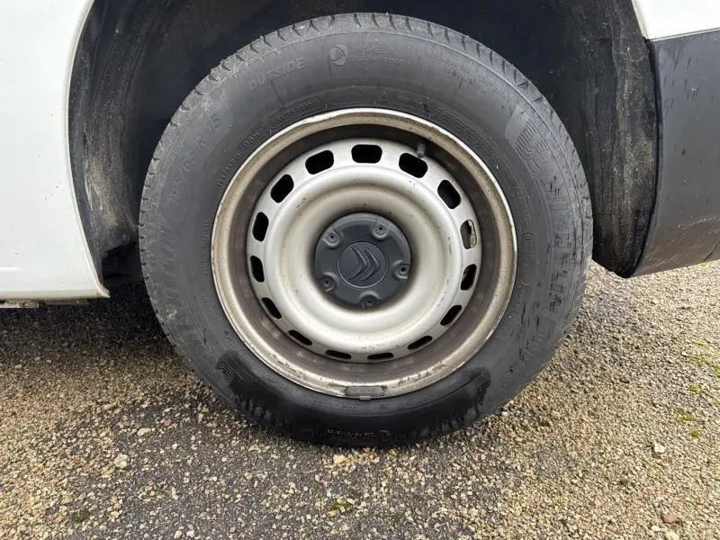 Gros plan sur la roue avant gauche du Citroën Berlingo Fourgon blanc Banquise avec jante tôle grise et logo Citroën au centre.